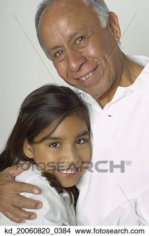 Picture - Hispanic grandfather and granddaughter hugging. Fotosearch