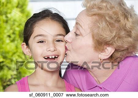 Hispanic grandmother kissing granddaughter on cheek View Large Photo Image Stock Photo - Hispanic grandmother kissing granddaughter on cheek. Fotosearch