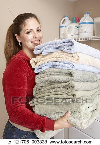 Stock Photo - Hispanic woman carrying folded towels. Fotosearch