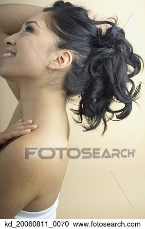 Stock Image - Hispanic woman holding up hair. Fotosearch