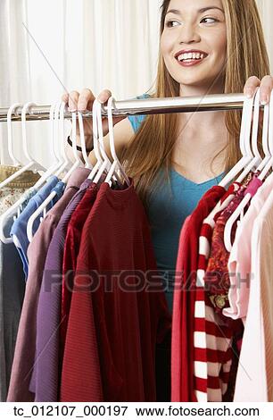 Stock Photo - Hispanic woman next to rack of clothing. Fotosearch