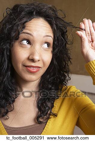 Stock Image - Hispanic woman playing with hair. Fotosearch