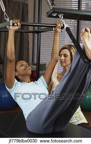 Stock Image - Indian woman exercising with personal trainer. Fotosearch