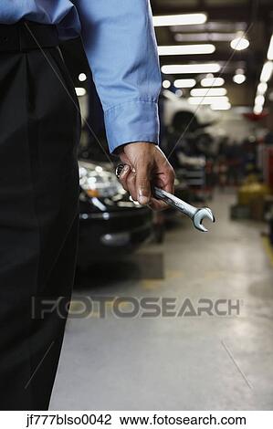 Stock Image - Male auto mechanic holding wrench. Fotosearch