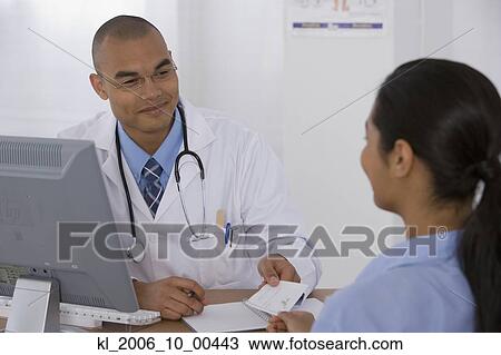 Stock Image - Male doctor handing prescription to patient. Fotosearch