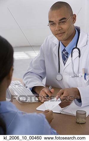 Stock Image - Male doctor handing prescription to patient. Fotosearch