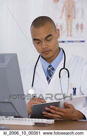 Stock Image - Male doctor writing in notebook. Fotosearch