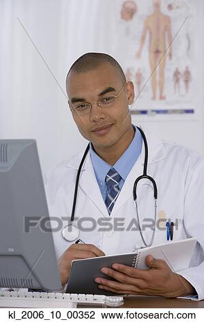 Stock Image - Male doctor writing in notebook. Fotosearch