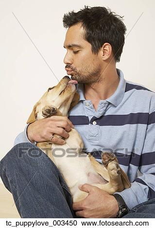 Stock Image - Mixed Race man kissing dog. Fotosearch