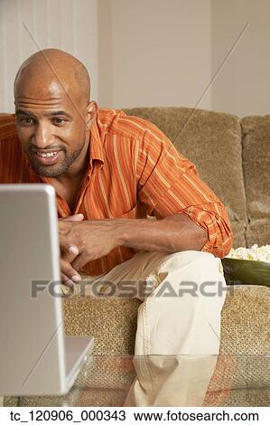 Stock Image - Mixed Race man looking at laptop. Fotosearch