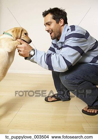 Picture - Mixed Race man playing with puppy dog. Fotosearch