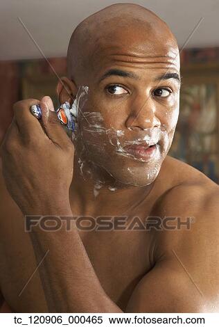 Stock Photography - Mixed Race man shaving in mirror. Fotosearch