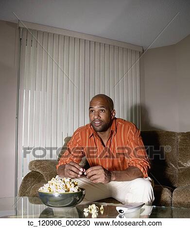 Stock Image - Mixed Race man watching television. Fotosearch