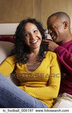 Multi-ethnic couple hugging on sofa View Large Photo Image Stock Photo - Multi-ethnic couple hugging on sofa. Fotosearch