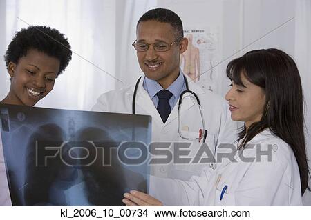 Picture - Multi-ethnic doctors and patient looking at x-ray. Fotosearch
