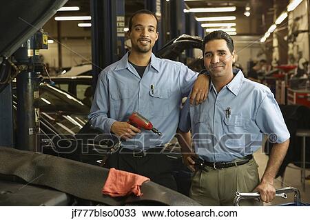 Stock Image - Multi-ethnic male auto mechanics in shop. Fotosearch