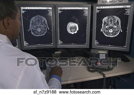 Stock Photo - Rear view of African male doctor reviewing at brain scans. Fotosearch