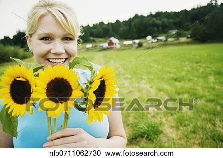 Woman holding sunflowers on farm View Large Photo Image Stock Image - Woman holding sunflowers on farm. Fotosearch