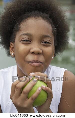 Stock Image - African American girl holding apple. Fotosearch