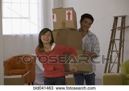 Stock Image - Asian couple carrying moving boxes. Fotosearch