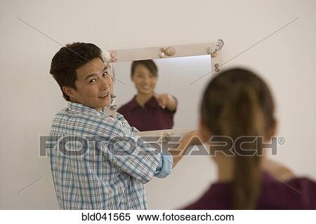Stock Photography - Asian couple hanging mirror. Fotosearch