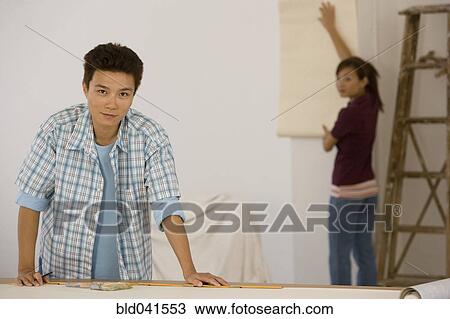 Stock Image - Asian couple hanging wall paper. Fotosearch