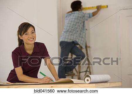 Stock Image - Asian couple hanging wall paper. Fotosearch