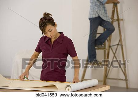 Stock Photo - Asian couple hanging wall paper. Fotosearch