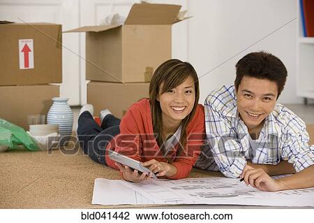 Asian couple looking at blueprints in new house View Large Photo Image Stock Image - Asian couple looking at blueprints in new house. Fotosearch