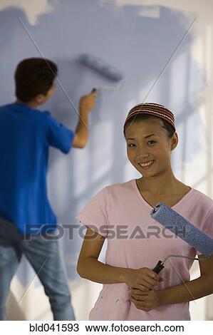 Stock Image - Asian couple painting interior of house. Fotosearch