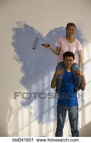 Stock Image - Asian couple painting interior of house. Fotosearch