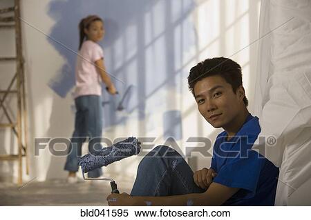 Stock Photography - Asian couple painting interior of house. Fotosearch