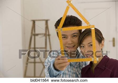 Asian couple with folding ruler shaped like house View Large Photo Image Picture - Asian couple with folding ruler shaped like house. Fotosearch