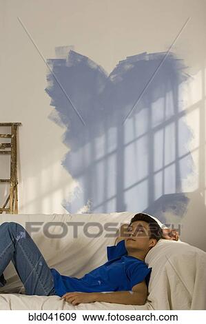 Stock Photo - Asian man in partially painted room. Fotosearch