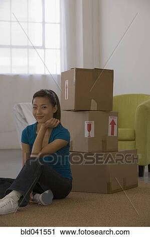 Asian woman sitting next to moving boxes View Large Photo Image Stock Image - Asian woman sitting next to moving boxes. Fotosearch