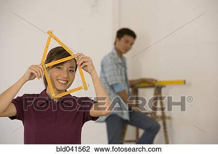 Stock Image - Asian woman with folding ruler shaped like house. Fotosearch
