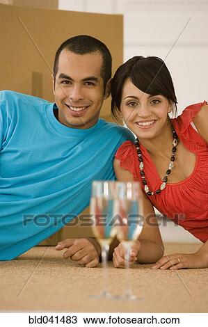 Stock Image - Couple and champagne in new house. Fotosearch
