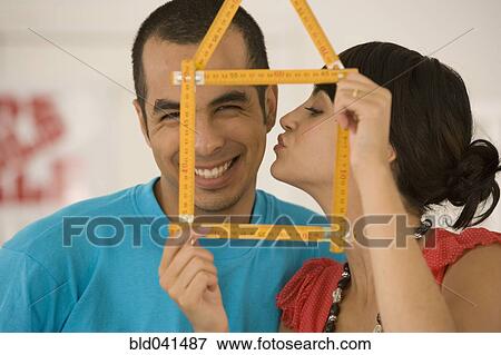 Stock Photo - Couple holding folding ruler shaped like house. Fotosearch