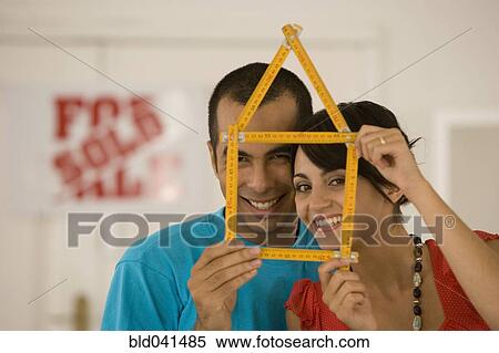 Stock Photography - Couple holding folding ruler shaped like house. Fotosearch