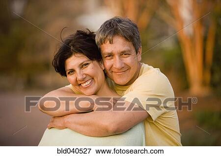 Stock Photo - Hispanic couple hugging in park. Fotosearch