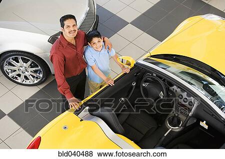 Stock Photo - Hispanic father and son next to new car. Fotosearch