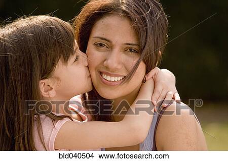 Picture - Hispanic girl kissing mother on cheek. Fotosearch