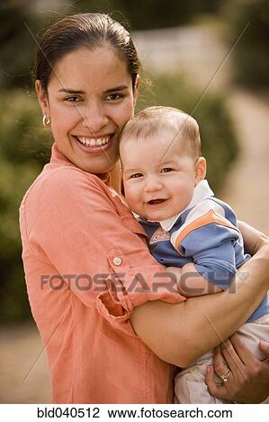 Stock Image - Hispanic mother holding baby. Fotosearch