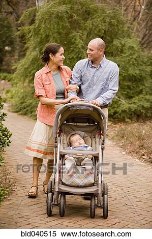 Stock Photography - Hispanic parents pushing baby in stroller. Fotosearch
