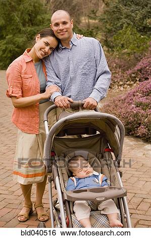 Stock Photograph - Hispanic parents with baby in stroller. Fotosearch