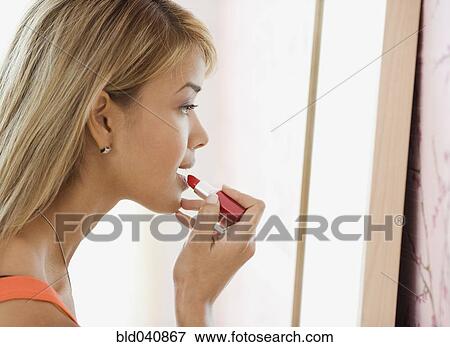 Stock Photo - Hispanic woman applying lipstick. Fotosearch