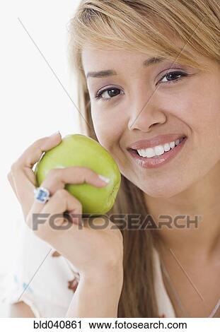 Stock Image - Hispanic woman eating apple. Fotosearch