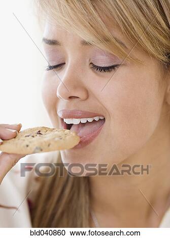 Stock Image - Hispanic woman eating cookie. Fotosearch