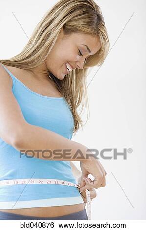 Stock Photograph - Hispanic woman measuring waist. Fotosearch