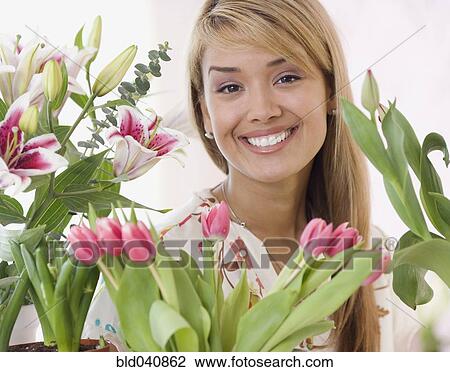 Stock Image - Hispanic woman surrounded by flowers. Fotosearch